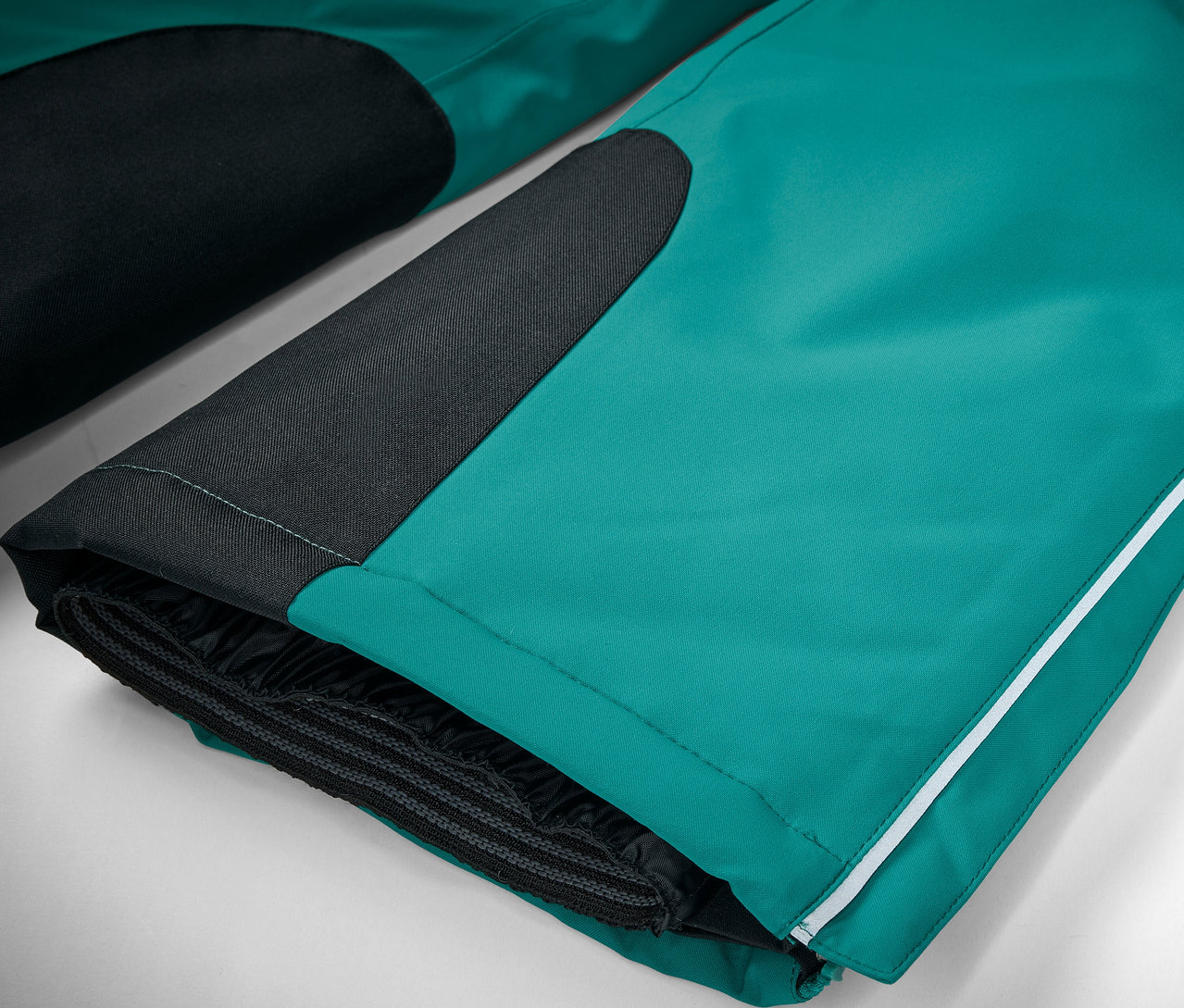 Detailaufnahme einer smaragdgrünen Skihose mit schwarzen Details und einem weißen Streifen.