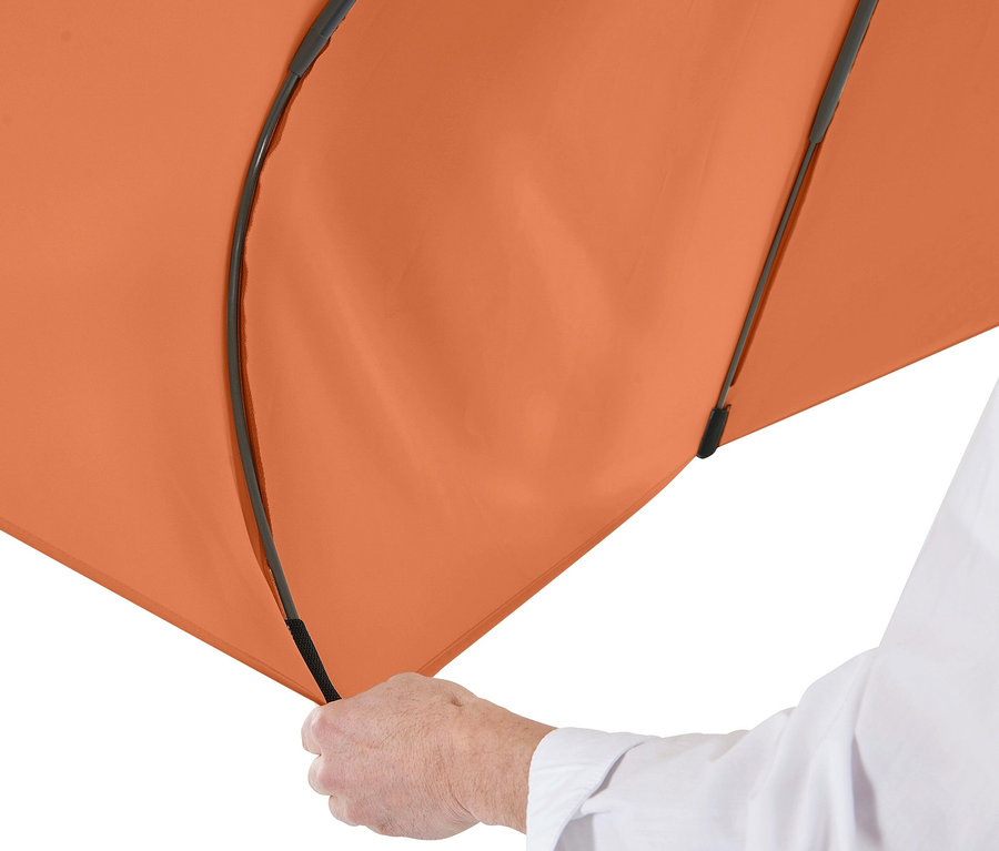 Eine Hand hält einen orangefarbenen Leco Sonnenschirm mit einem Durchmesser von 300 cm.