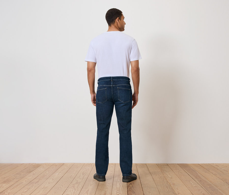 Mann steht mit dem Rücken zur Kamera und trägt Jeans und ein T-Shirt.