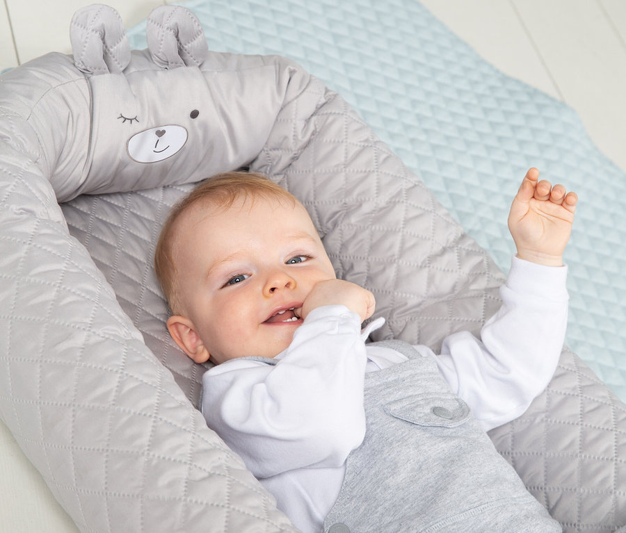 Ein Baby liegt in einer grauen Roba Babylounge.