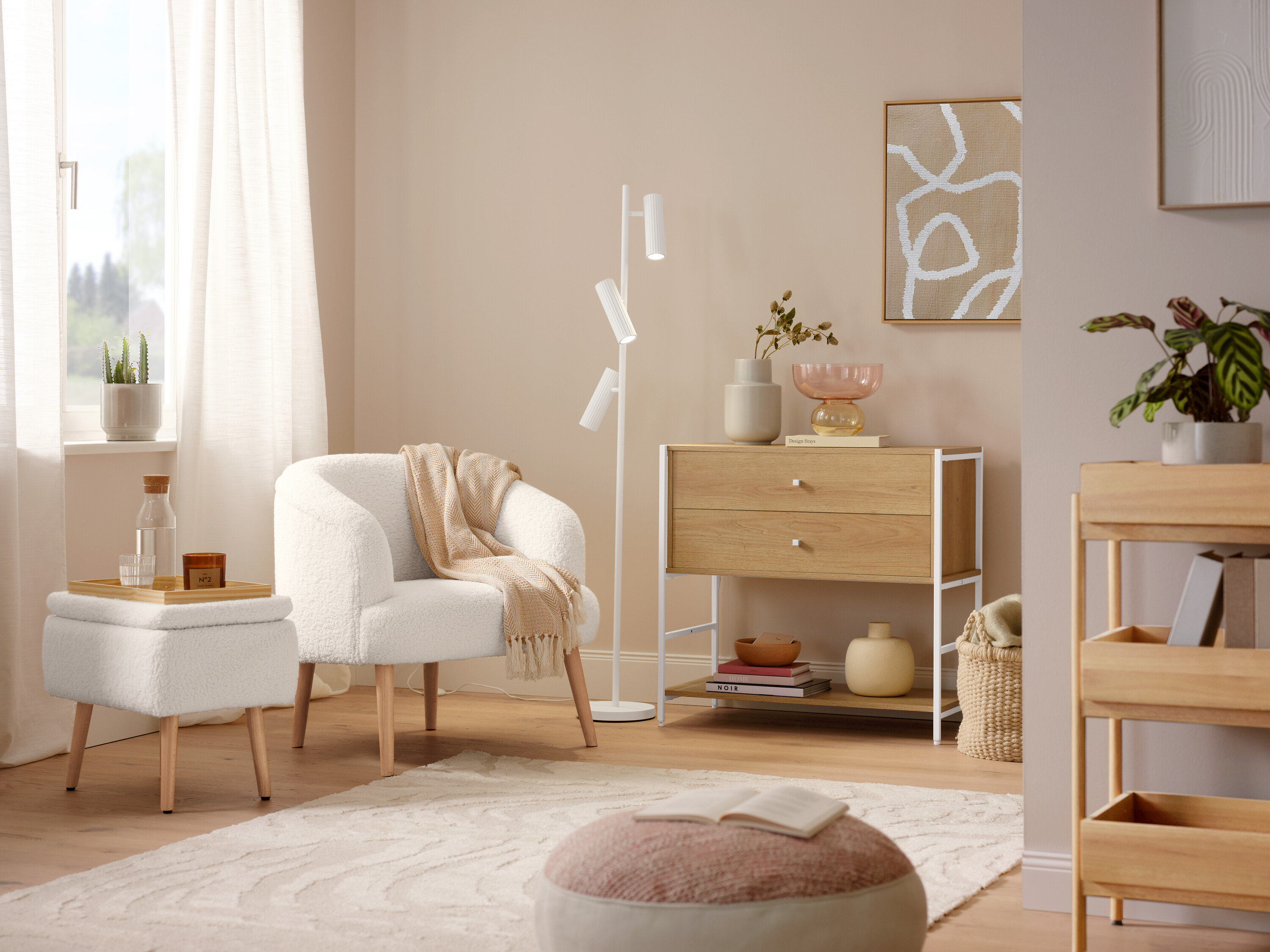 Ein Bouclé-Sessel mit Holzbeinen steht neben einer Trio Stehleuchte »Soka«. Ein grauer Teppich »Cosmo «Waves liegt auf dem Boden.