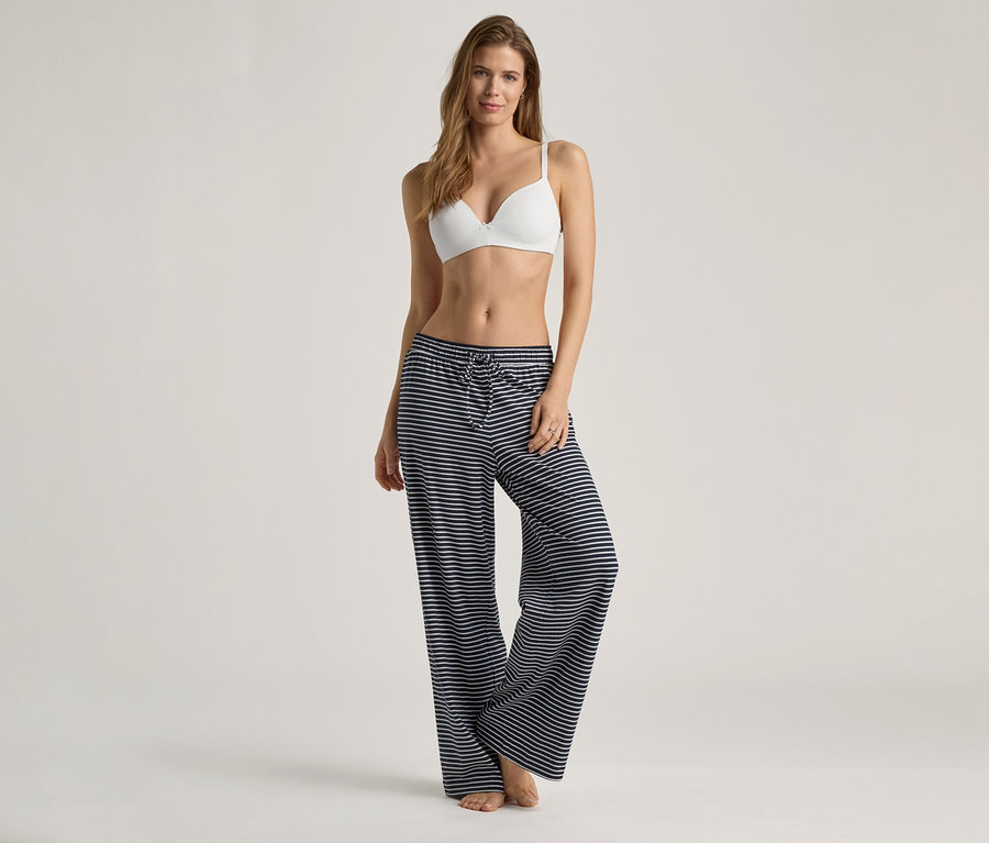 Frau trägt einen weißen Softschalen-BH und eine blau-weiß gestreifte Hose.