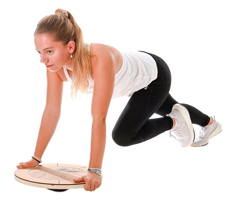 Frau in Sportkleidung balanciert auf F2 Round Balance Plate.