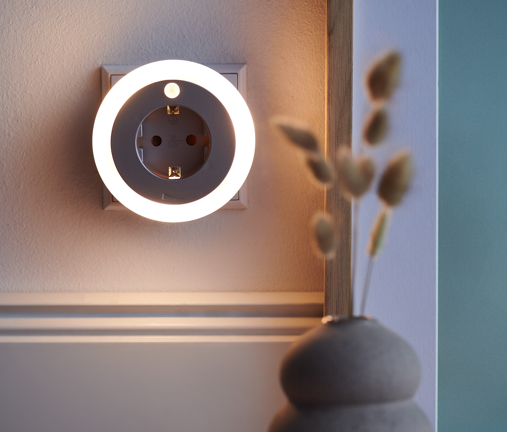 An der Wand befindet sich ein LED-Nachtlicht mit Steckdose.