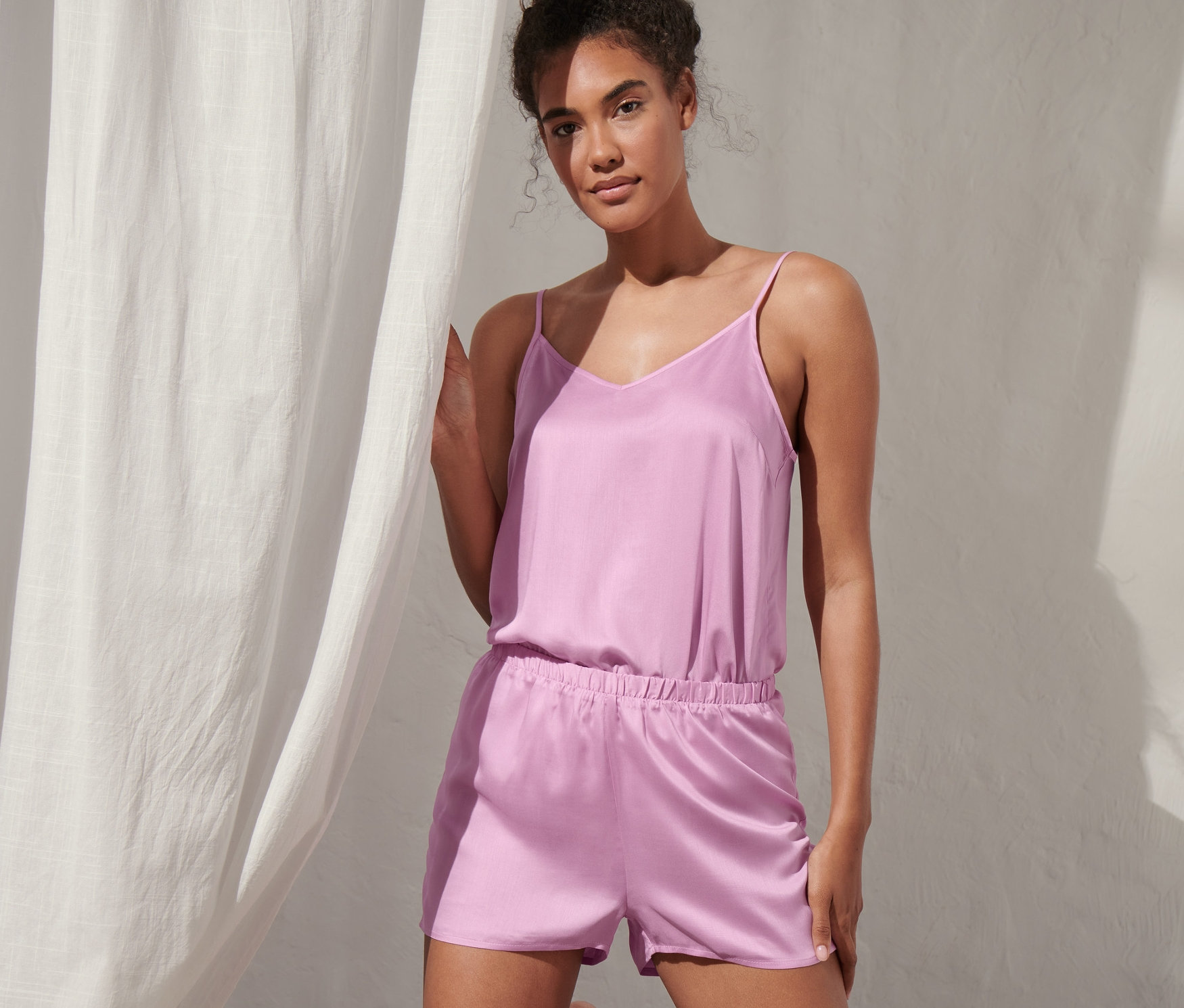 Frau kniet auf einer Matratze und trägt einen Shorty-Pyjama.