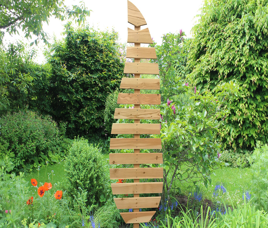 Eine hölzerne Rankhilfe »Magnolia« steht in einem Garten.