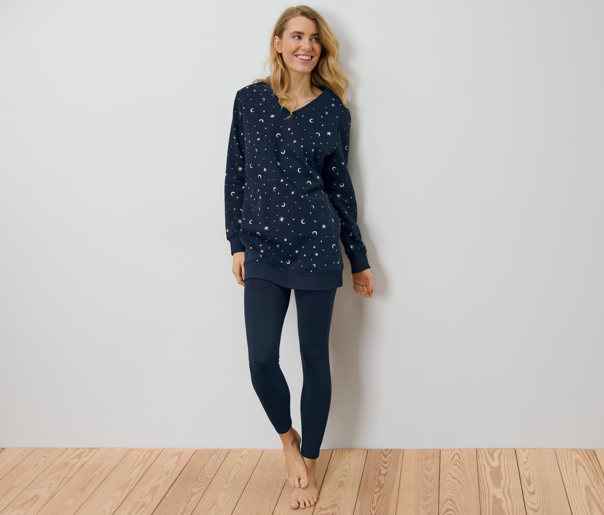 Frau steht barfuß und trägt einen Leggings-Pyjama.