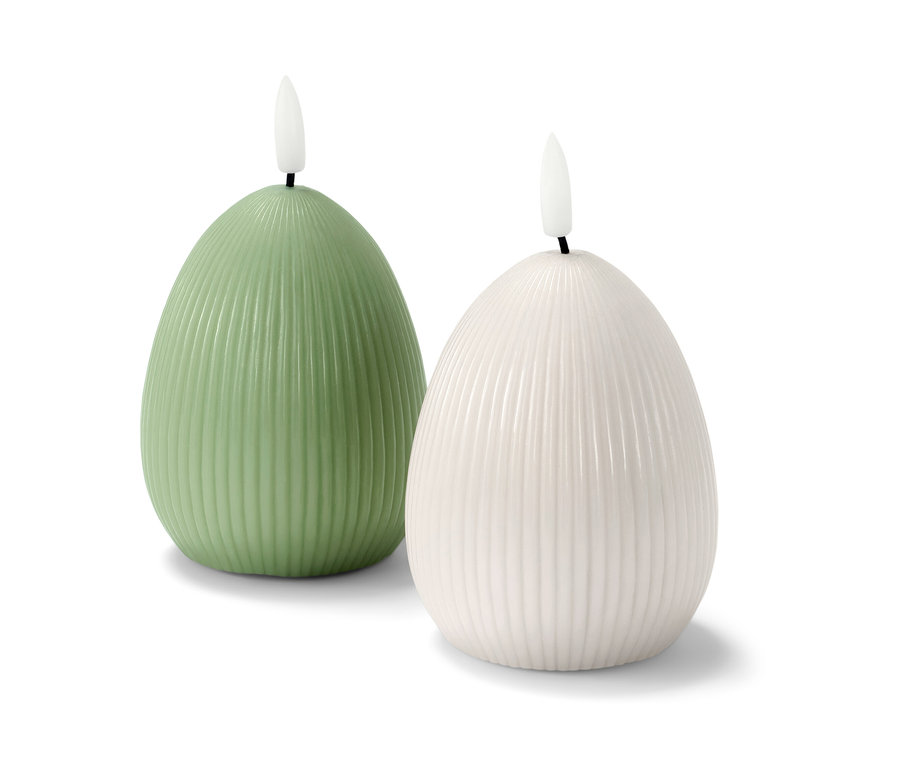 Zwei LED-Echtwachskerzen, eine grün, eine weiß, stehen nebeneinander auf einem weißen Hintergrund.