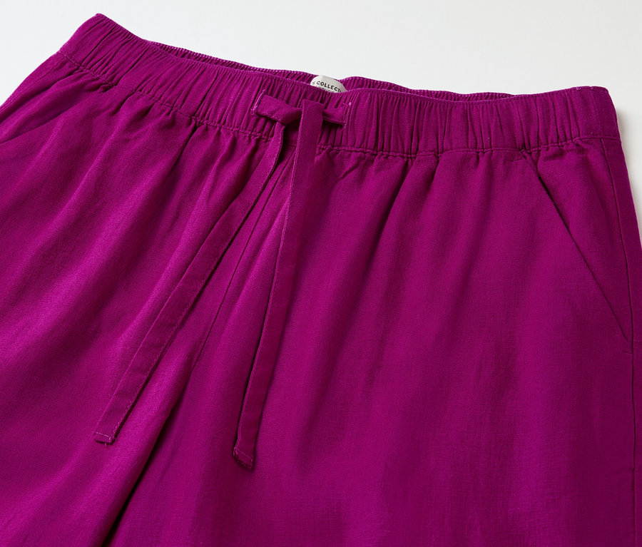 Detailaufnahme einer Leinenhose in Beere mit elastischem Bund und Kordelzug.