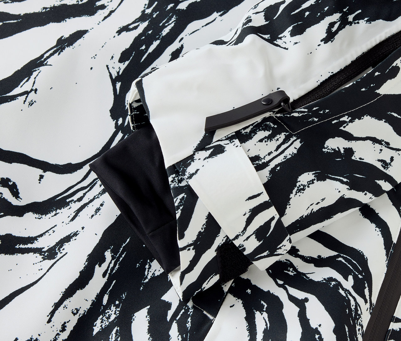 Detail einer Jacke mit Zebramuster in Weiß und Schwarz, Ärmel und Reißverschluss sichtbar.