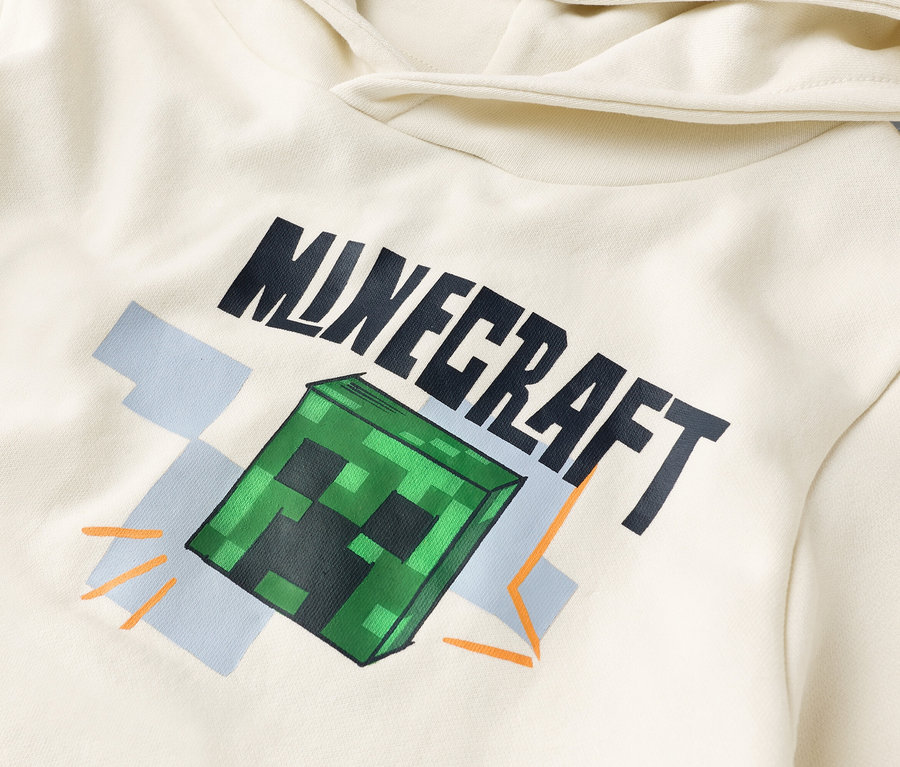 Detailansicht eines cremefarbenen Kapuzenpullovers mit dem Aufdruck "Minecraft" und einem grünen Creeper-Block.