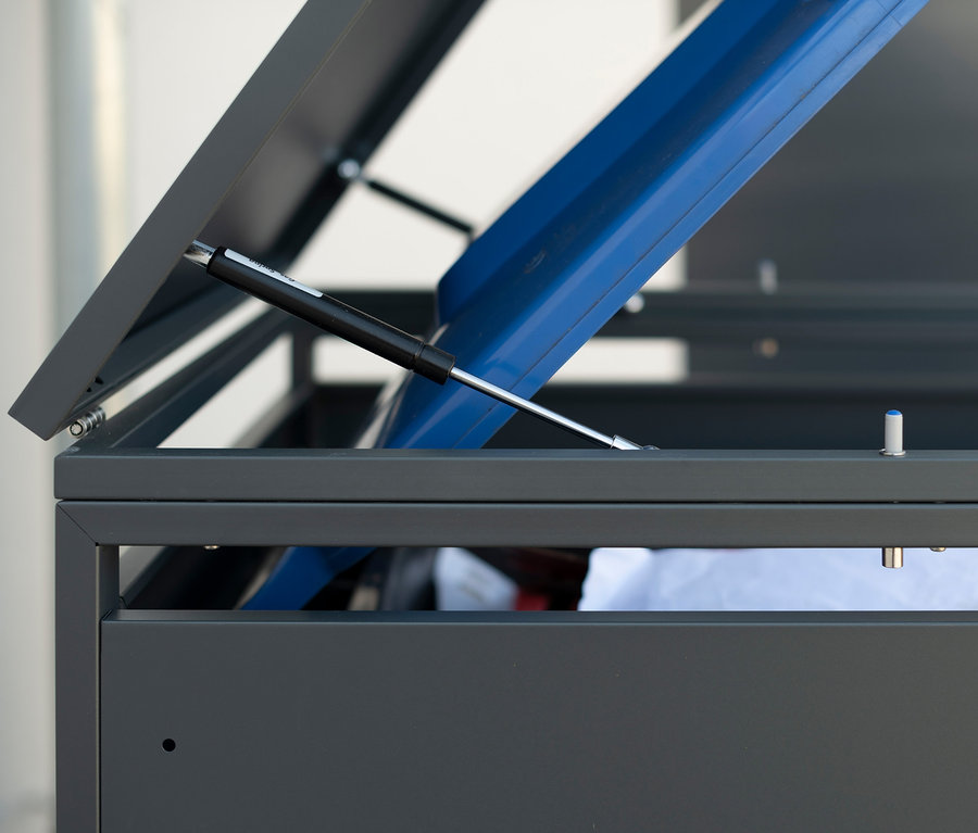 Geöffneter Mülltonnenbox aus Stahl mit blauem Deckel im Inneren.