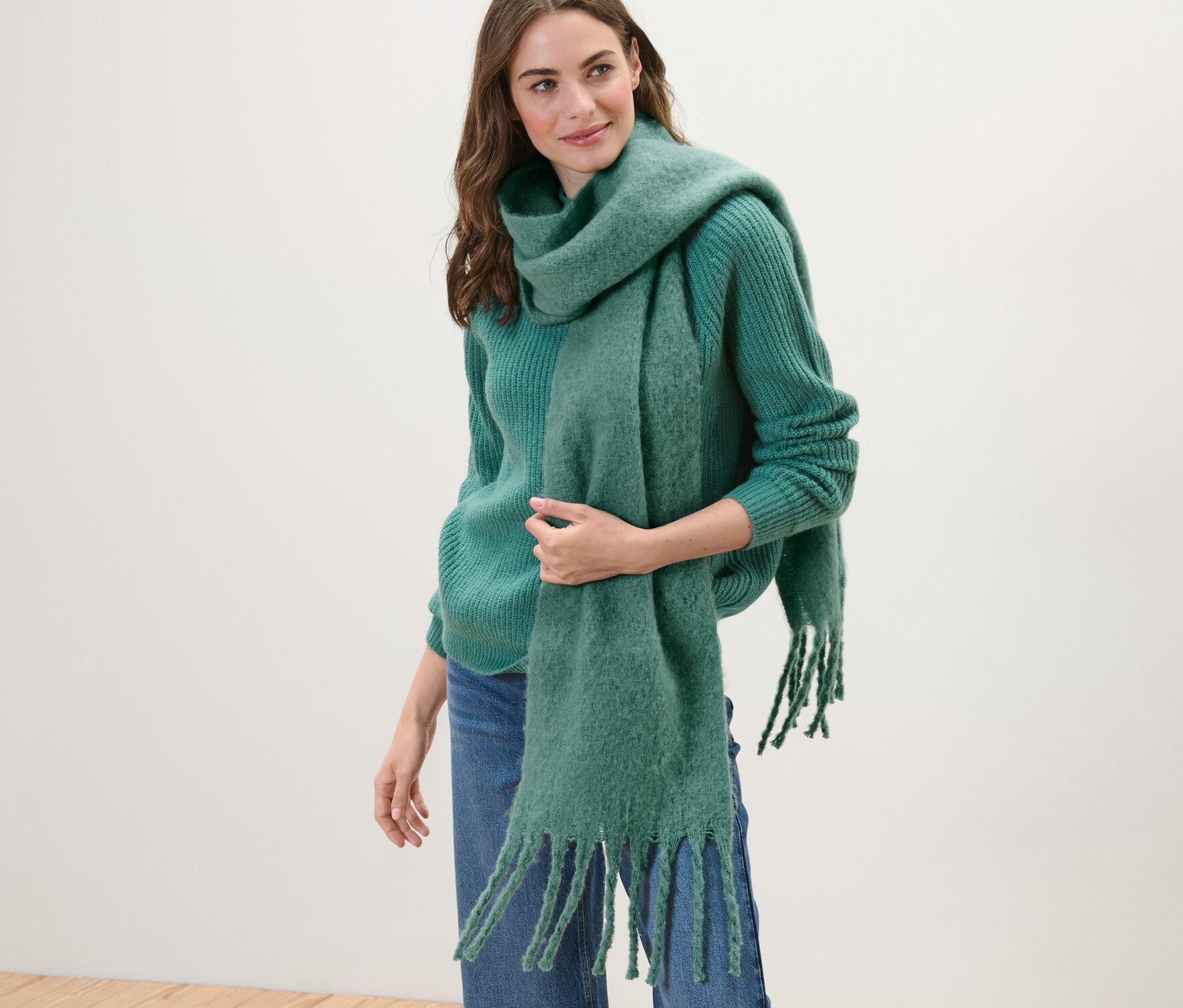 Frau trägt grünen Strickpullover und Webschal, grün.