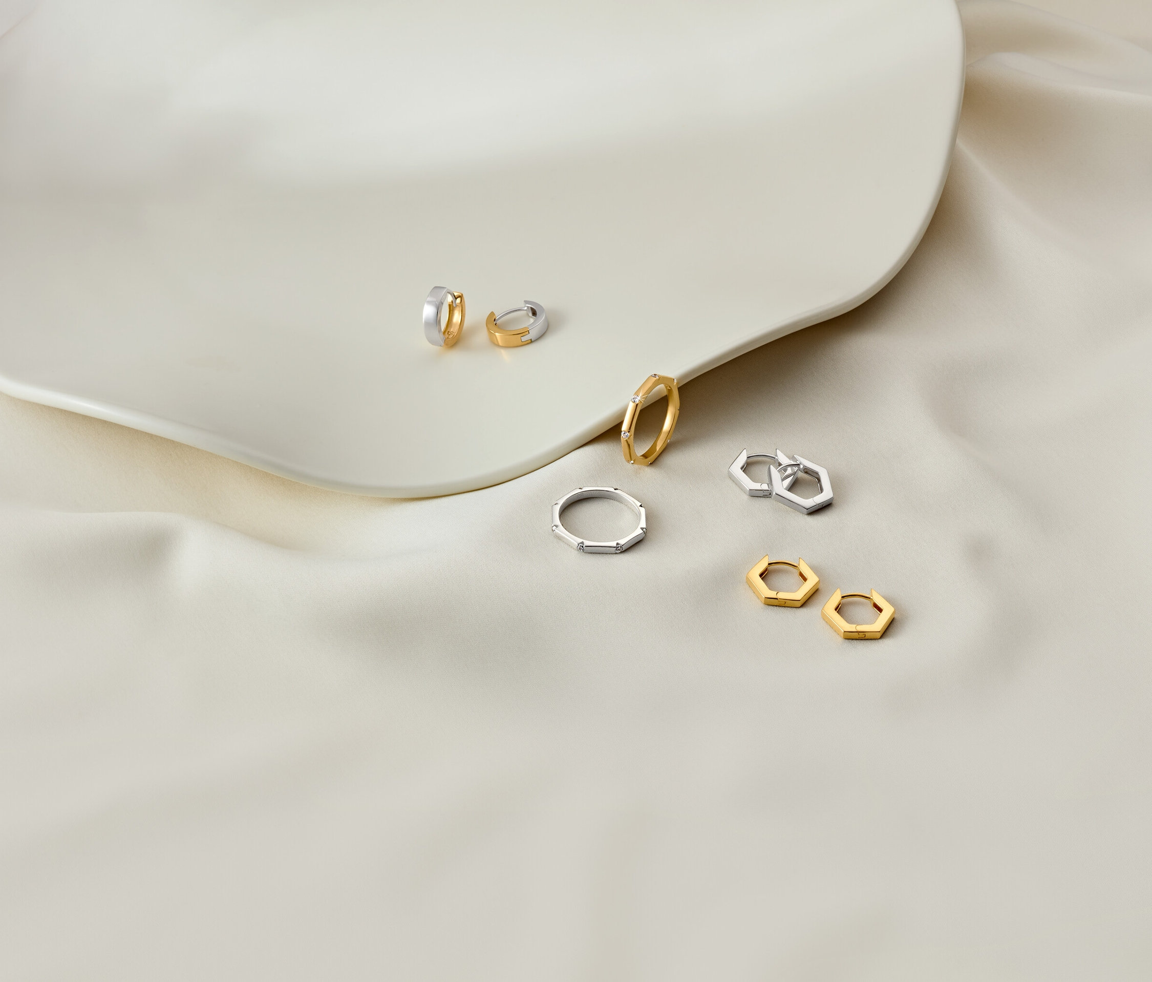 Ohrringe und Ringe auf einem weißen Teller und weißem Stoff.