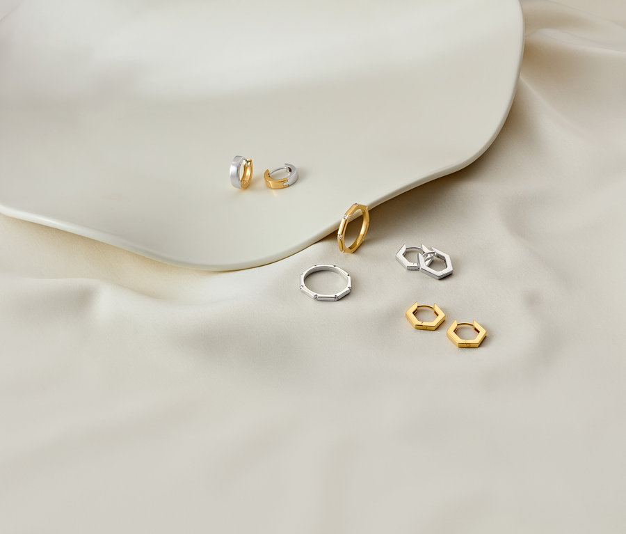 Ohrringe und Ringe auf einem weißen Teller und weißem Stoff.