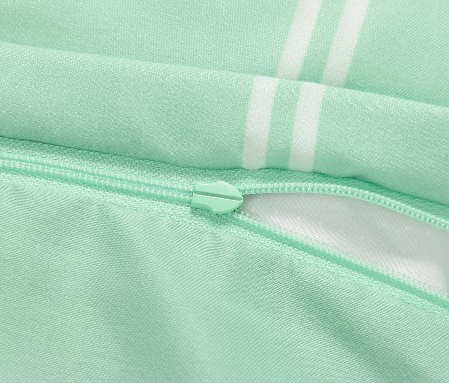 Detail eines hellgrünen Kissenbezugs mit Reißverschluss und weißen Streifen.