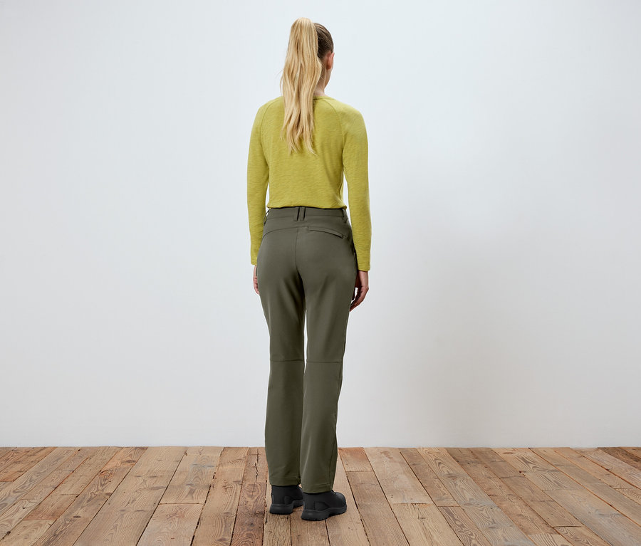 Frau steht mit dem Rücken zur Kamera, trägt eine grüne Hose und ein gelbes Oberteil.