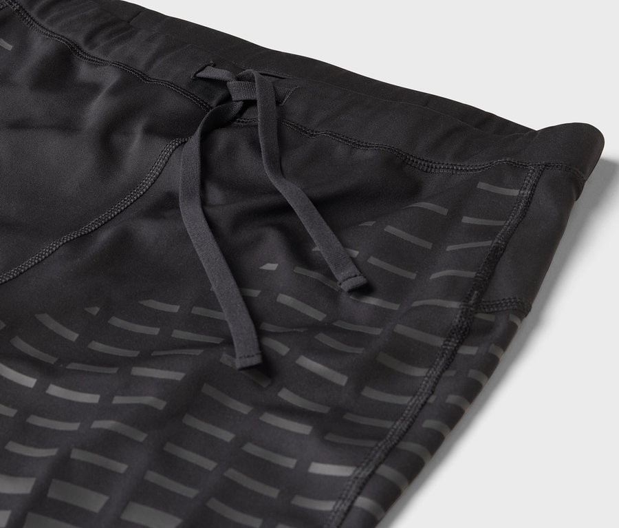 Detailaufnahme einer schwarzen Sportleggings mit Kordelzug und geometrischem Muster.