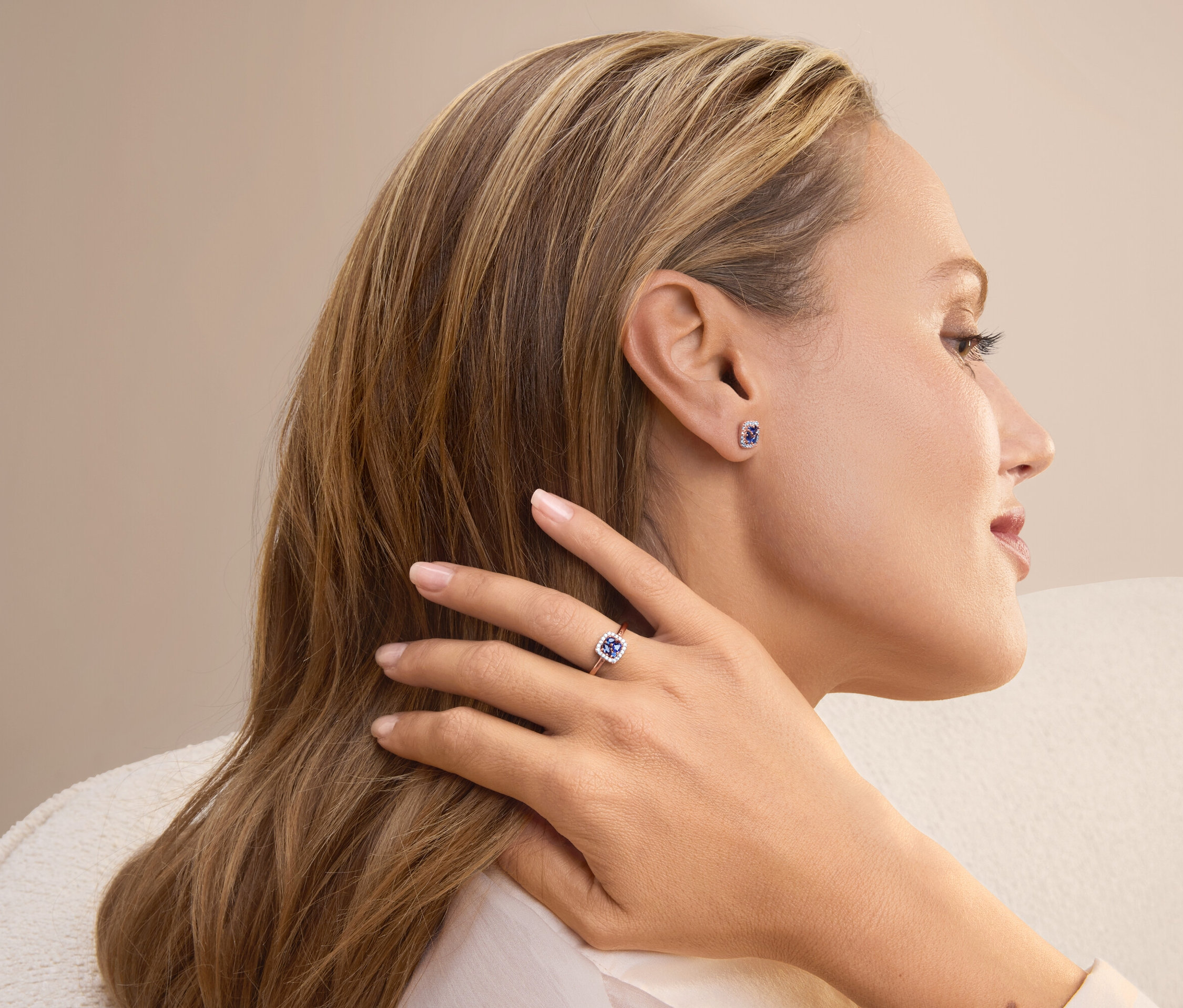 Profil einer blonden Frau, die einen Ring und Ohrringe mit blauen Steinen trägt.