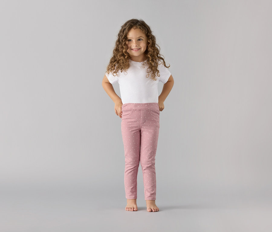 Lächelndes Mädchen posiert in Kinder-Jeggings ‒ Fit »Ida« und weißem T-Shirt.