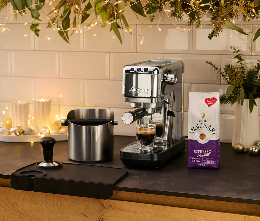 Auf einer Küchentheke steht eine silberne »Lapressa« Siebträgermaschine neben einer Tasse Espresso.