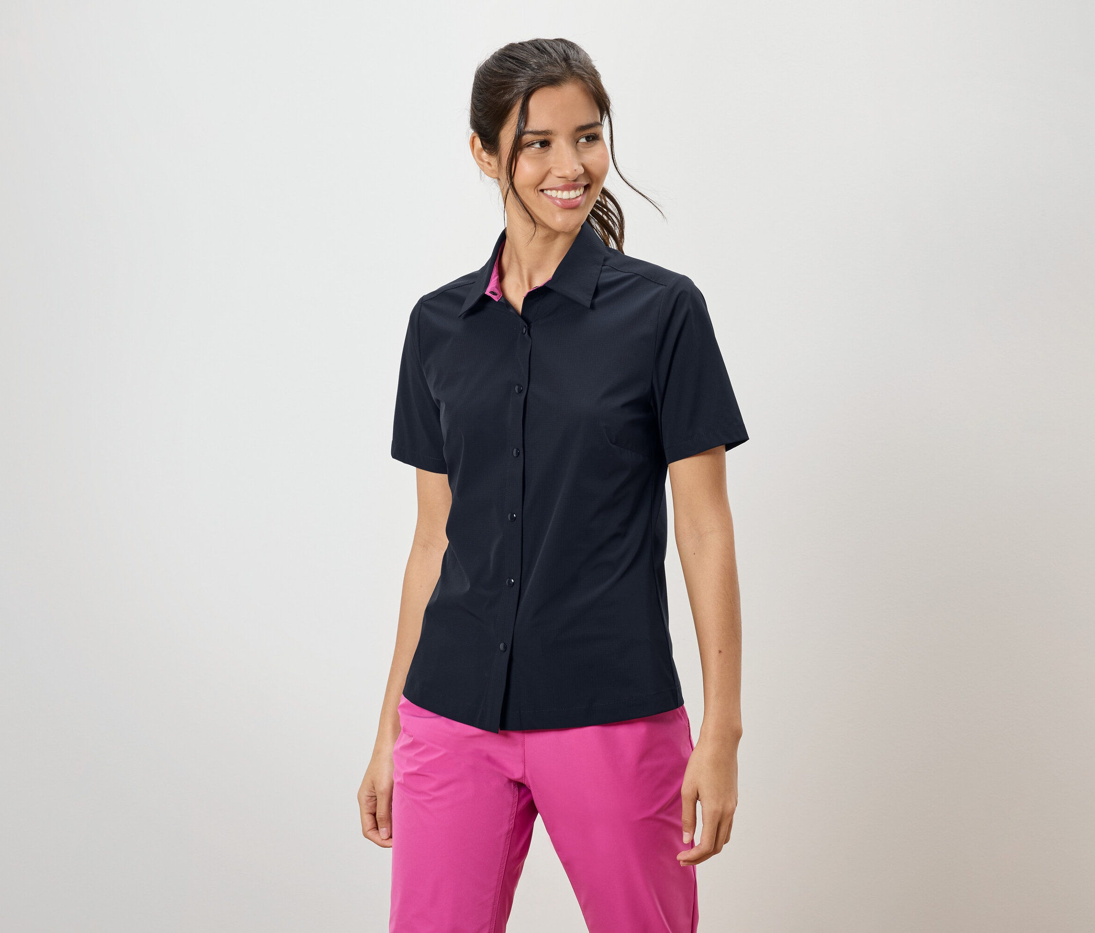 Frau trägt ein marineblaues kurzärmeliges Hemd und pinke Hosen.