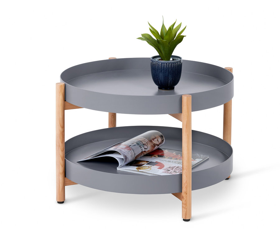 Ein runder Couchtisch mit Extra-Ablage in Grau mit einer Pflanze und einer Zeitschrift darauf.