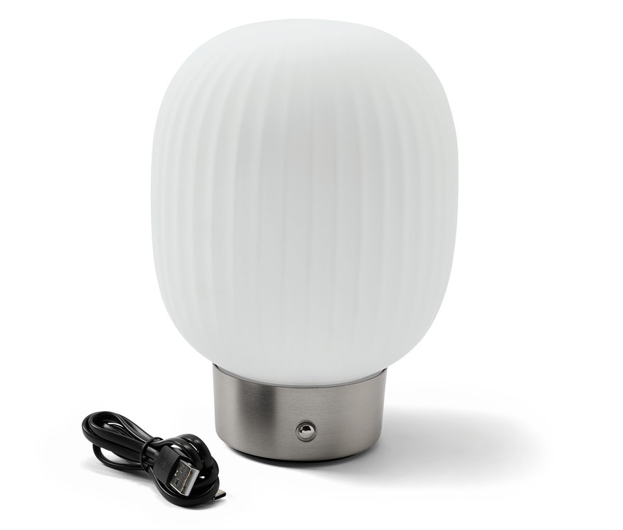 Eine LED-Akku-Tischleuchte mit Glasschirm steht neben einem schwarzen Ladekabel.