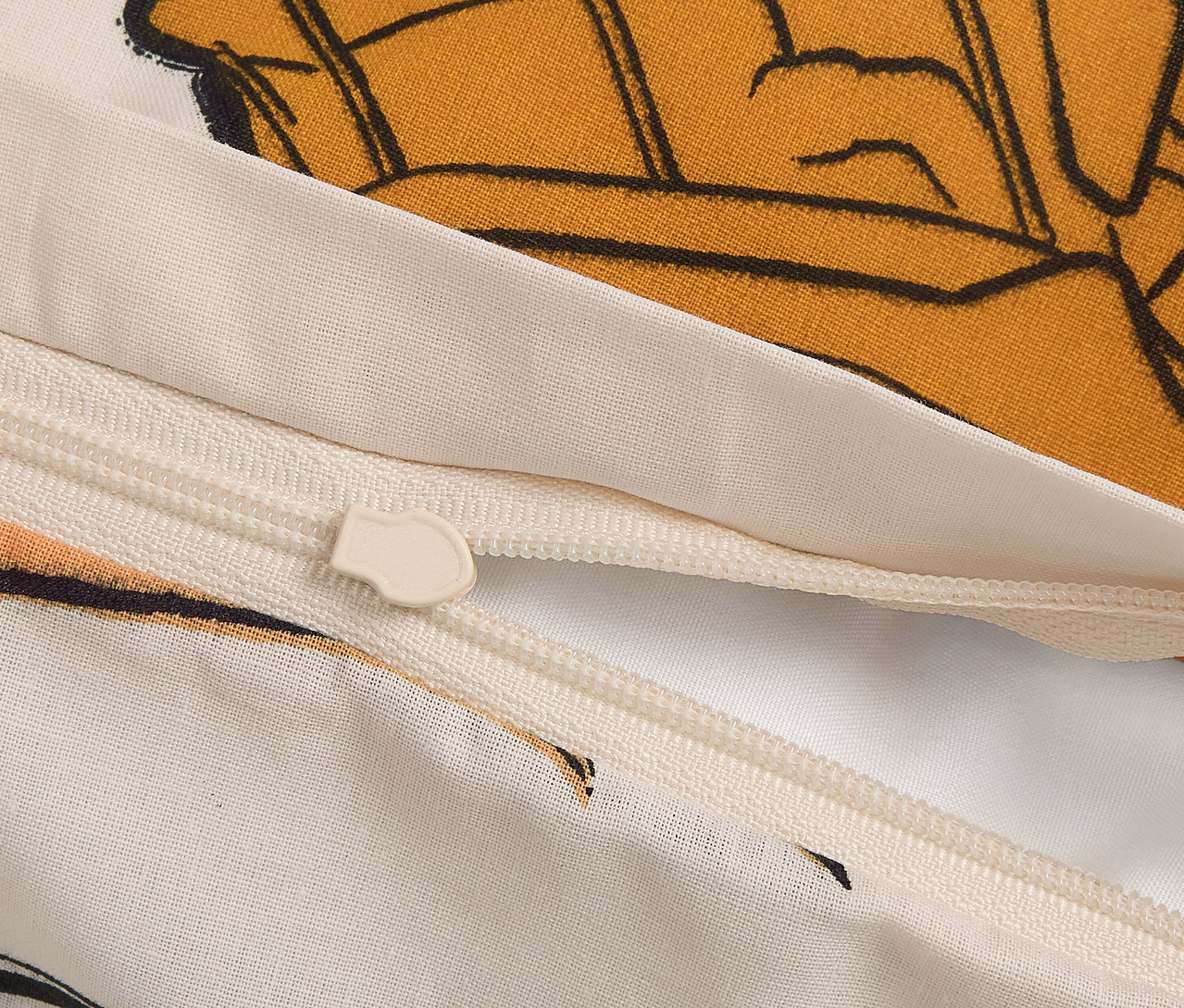 Detailaufnahme eines Reißverschlusses an einem Bettbezug mit Cartoon-Motiv.