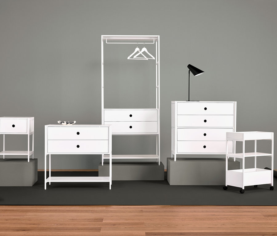 Anordnung von weißen Möbeln mit Nachttisch, Kommode mit Schubladen, Kleiderständer, Lampe und Regalen.