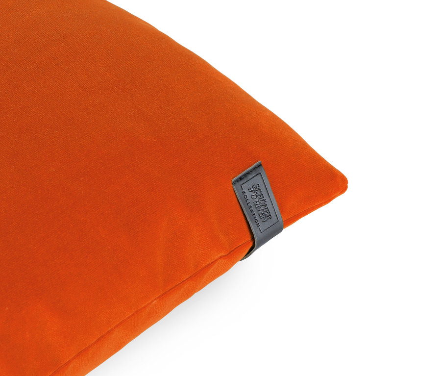 Detailaufnahme eines orangefarbenen Kissens mit schwarzem Etikett in der oberen rechten Ecke.