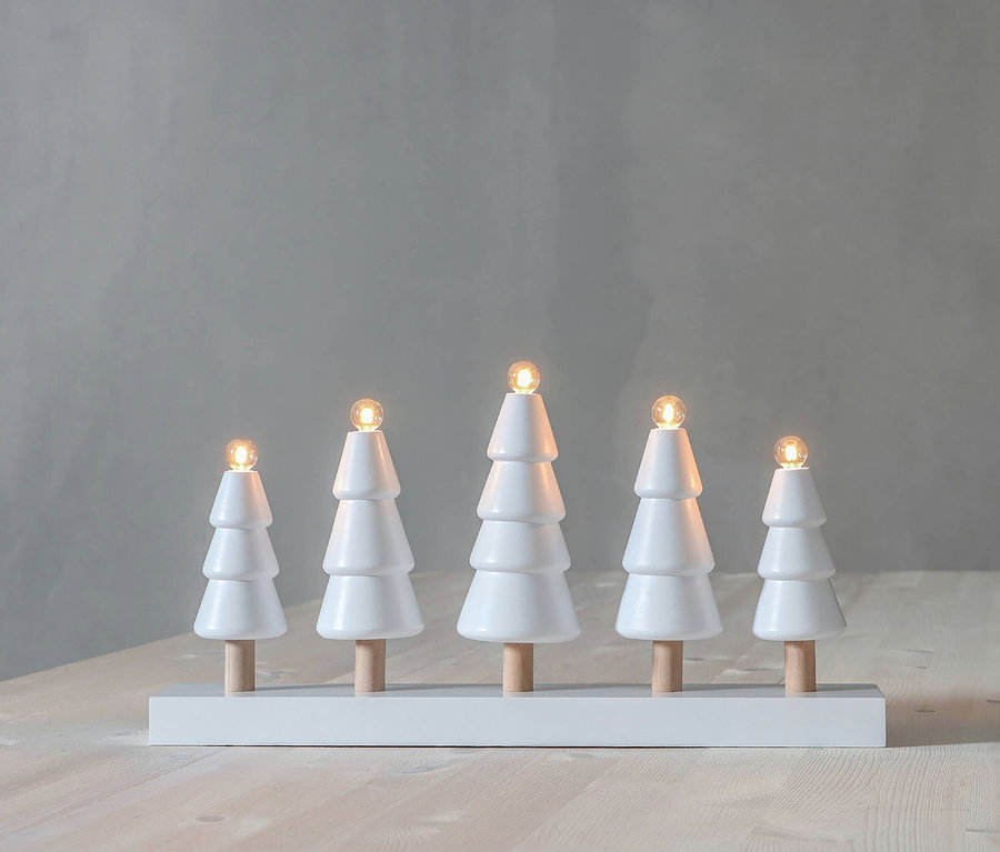 Fünf weiße Bäume mit Holzstämmen stehen auf einem weißen Sockel vor einem grauen Hintergrund.