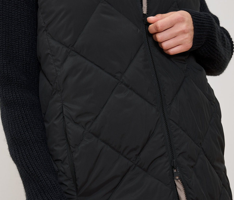 Frau schliesst eine schwarze Steppweste.