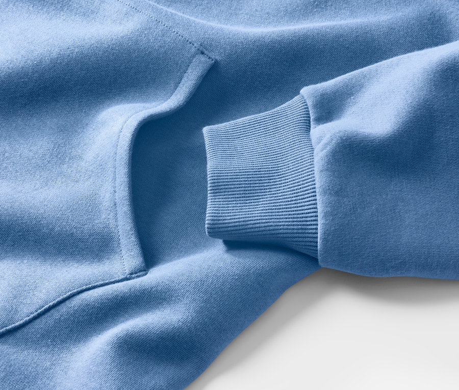 Detailansicht eines hellblauen Kapuzenpullovers, der eine Tasche und einen gerippten Ärmel zeigt.