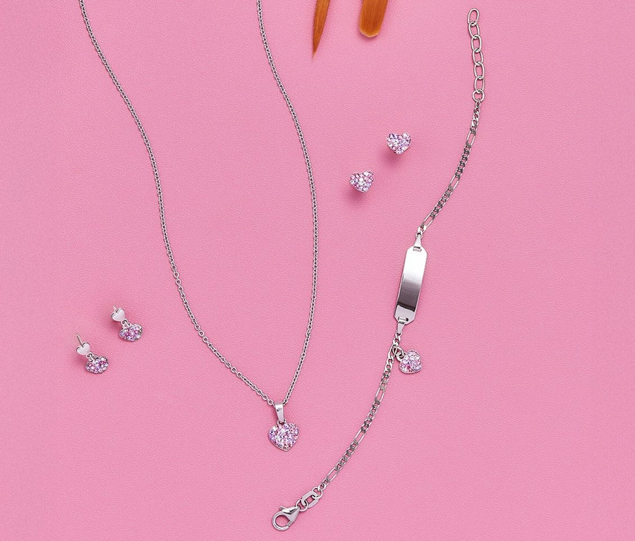 Herz-und-Figaro-Armschmuck aus 925er Silber mit passenden Ohrringen und Halskette auf rosafarbenem Hintergrund.