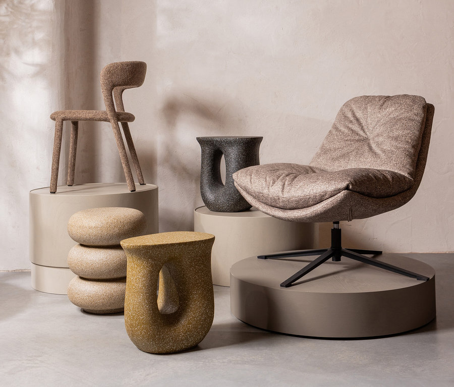 Verschiedene Möbelstücke, darunter ein Stuhl und ein Sessel, sind auf Podesten in einem Raum ausgestellt.