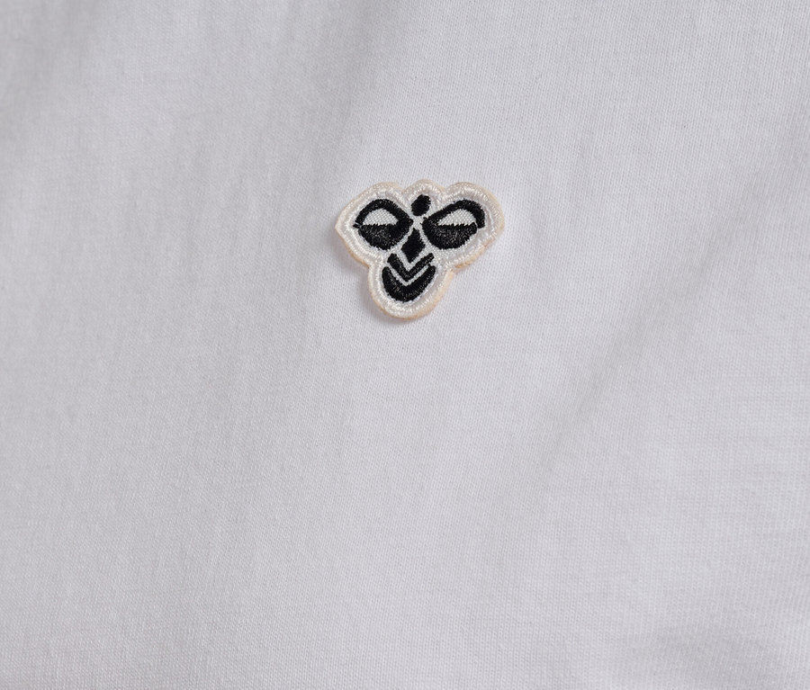 Nahaufnahme eines weißen hummel® Damen-T-Shirts mit kleinem, gesticktem Logo.