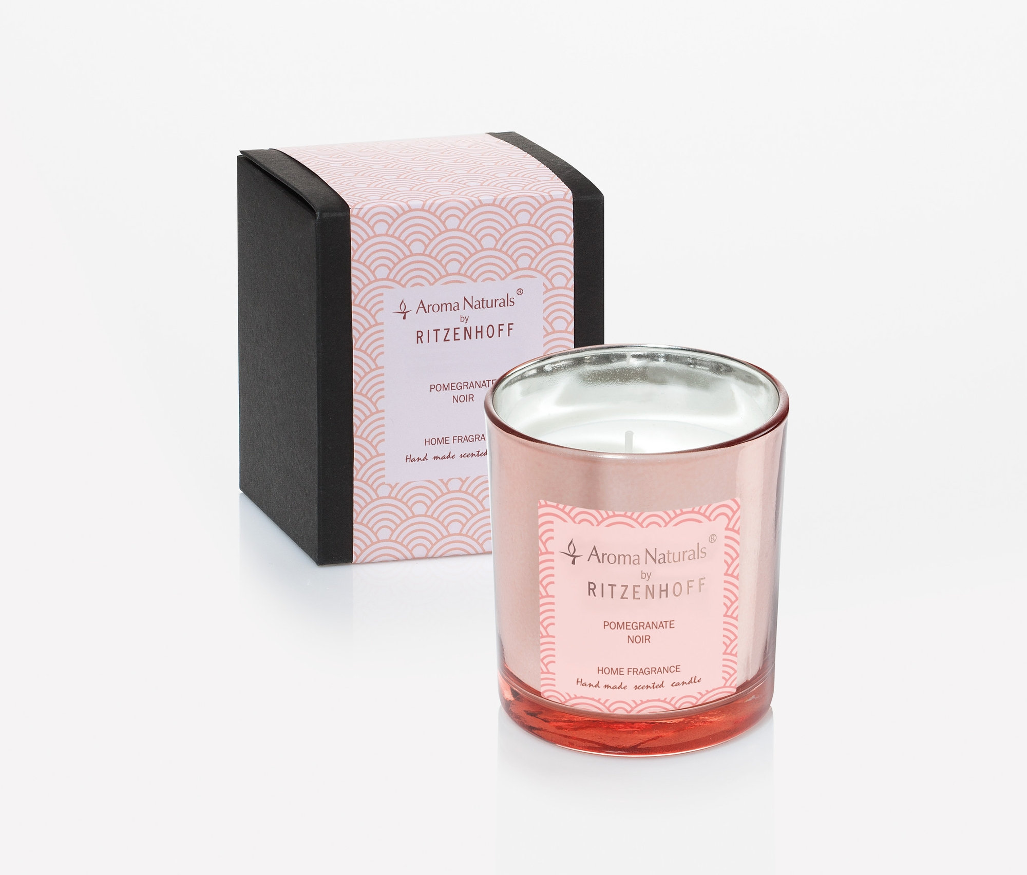 Eine rosa Kerze in einem Glas neben einer Schachtel.