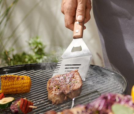 Mann grillt Steak mit BBQ-Multitool.