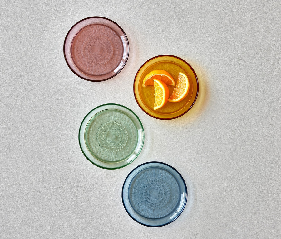Vier Bitz Glasteller »Kusintha«, 18 cm, rosa, grün, blau und orange, wobei auf dem orangenen Teller Orangenstücke liegen.