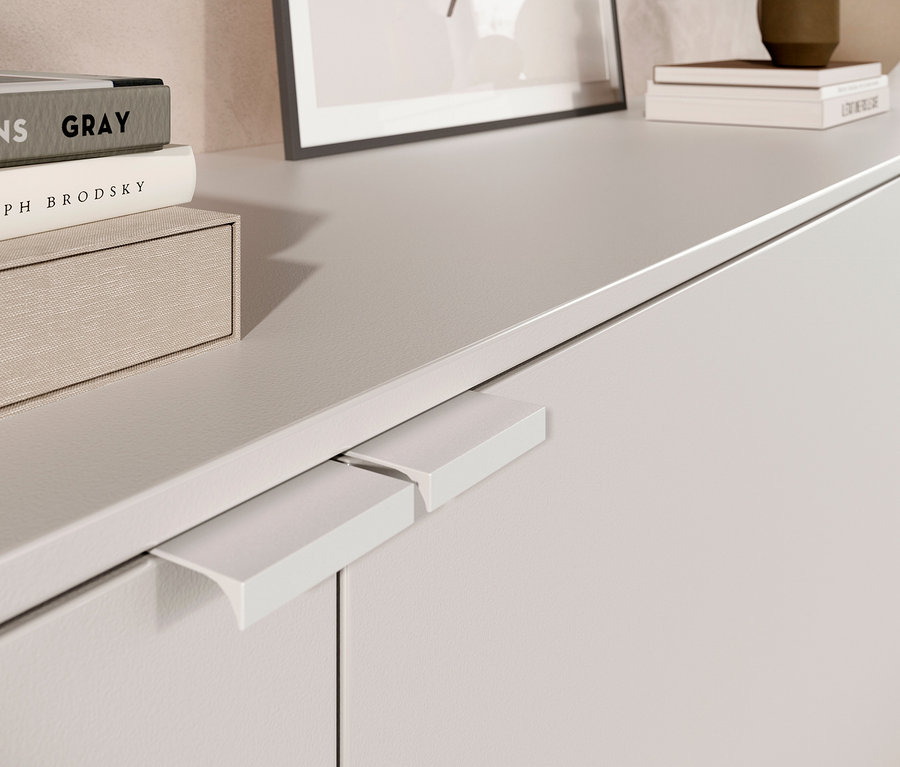 Detailansicht eines weißen Sideboards mit Büchern und Rahmen oben drauf.