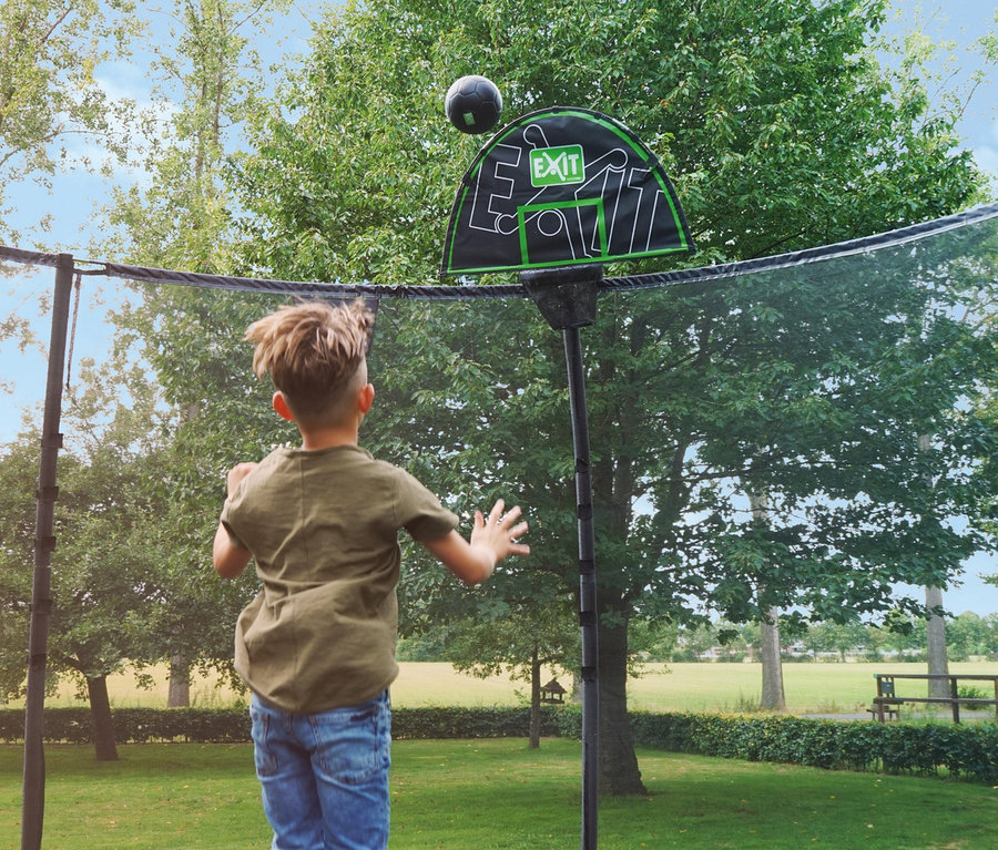 Junge spielt mit schwarzem Ball auf einem Trampolin mit EXIT Trampolin-Korb, grün-schwarz.