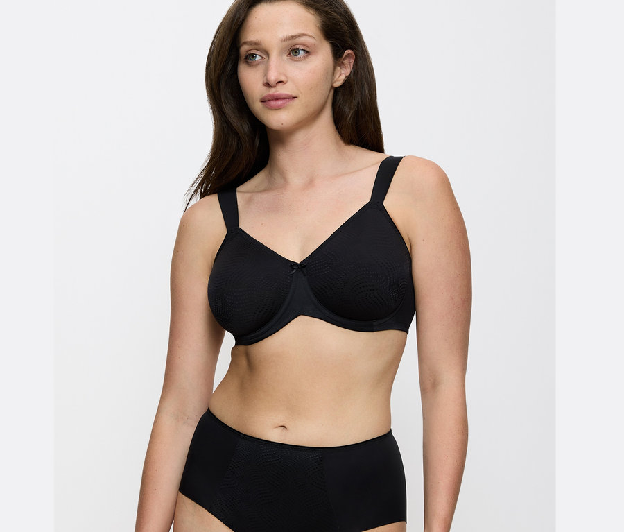 Porträt einer Frau, die einen schwarzen Triumph Essential »Minimizer W X« BH trägt.