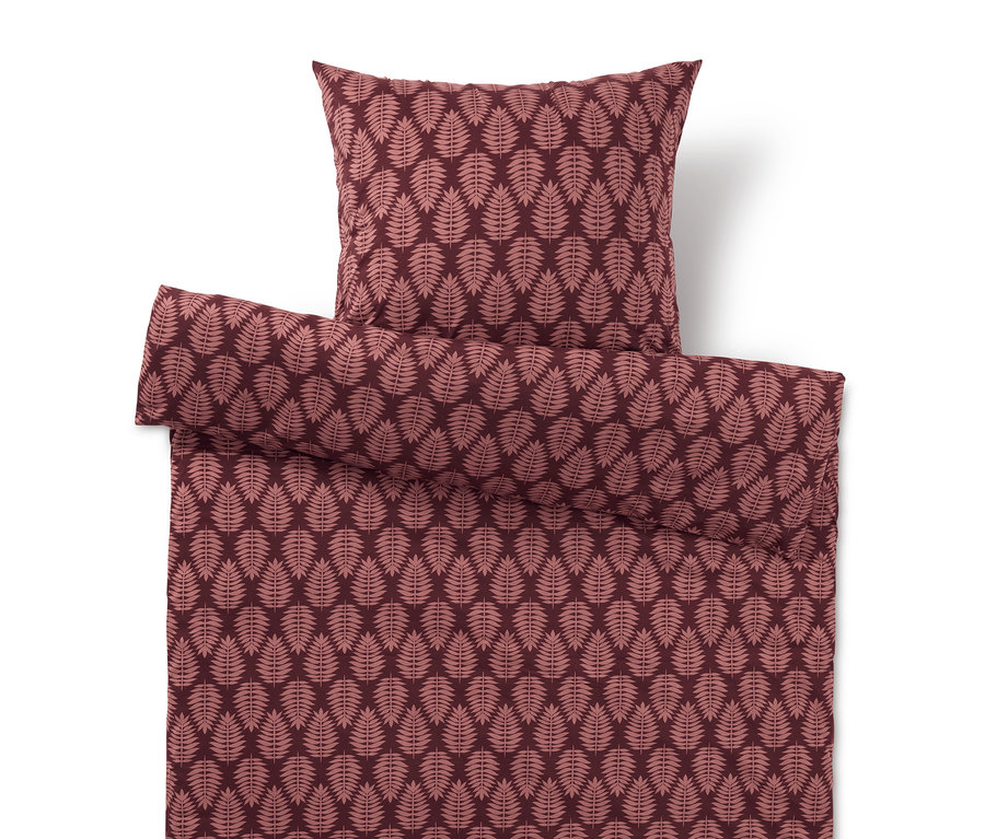 Bettbezug und Kissen mit Blattmuster in Rottönen.