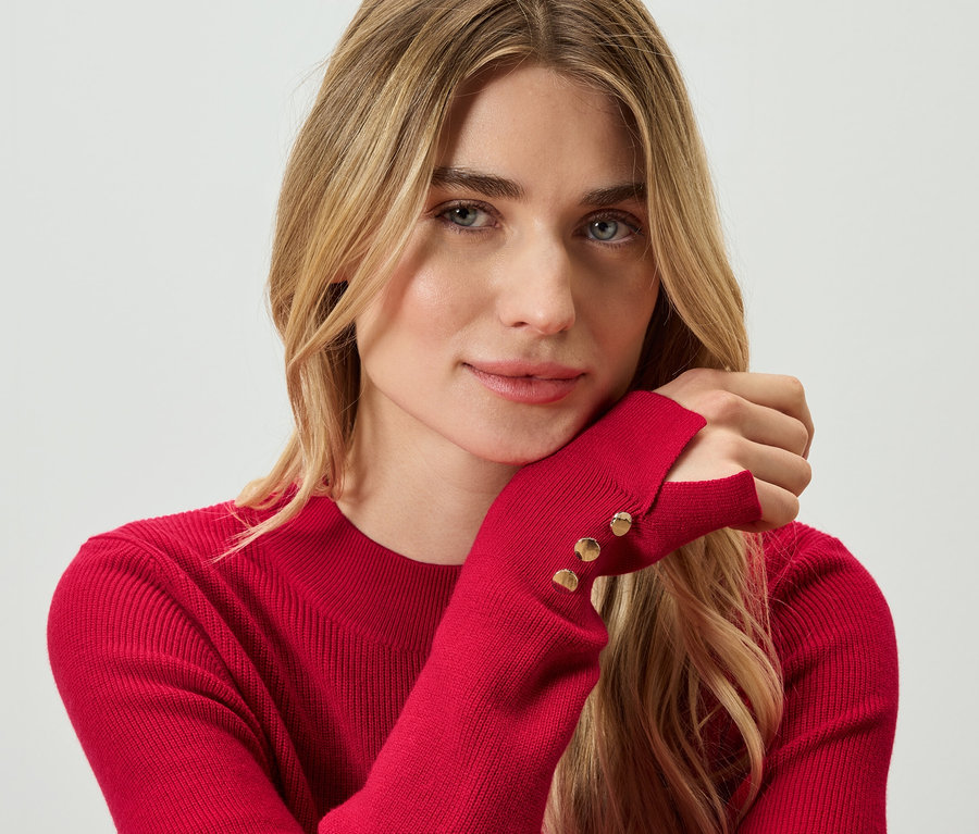 Porträt einer blonden Frau in einem roten Pullover.