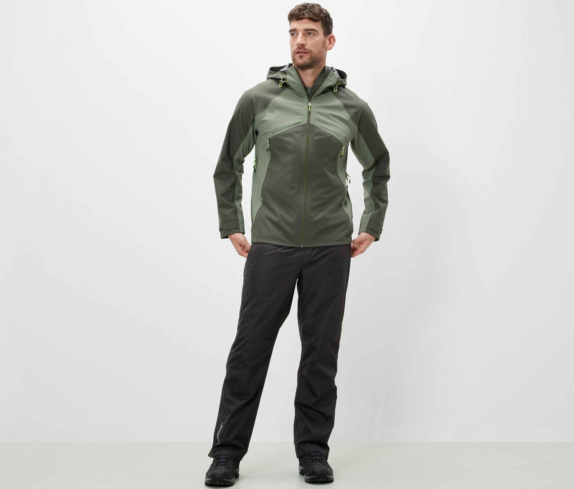 Mann steht und trägt eine High-Tech-Regenhose und eine Jacke.