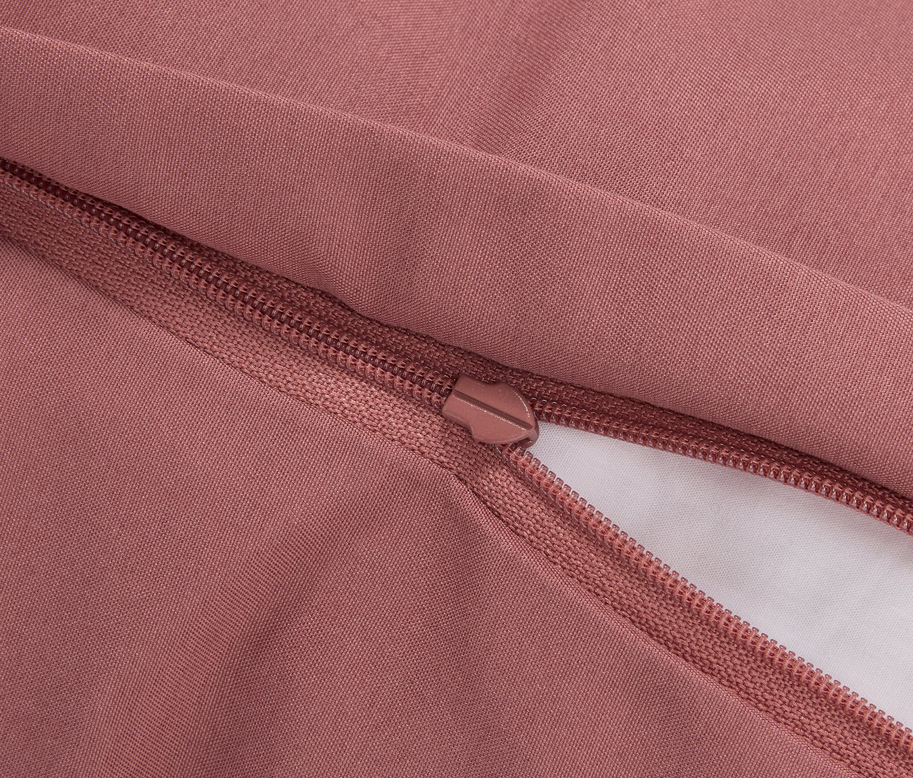 Detailaufnahme eines rosafarbenen Bettbezugs mit Reißverschluss.