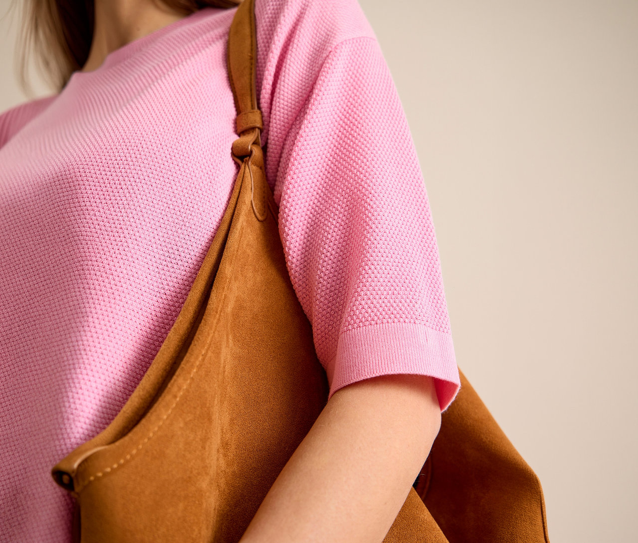 Frau trägt einen pinkfarbenen CECIL Kurzarmpullover und eine braune Tasche über der Schulter.