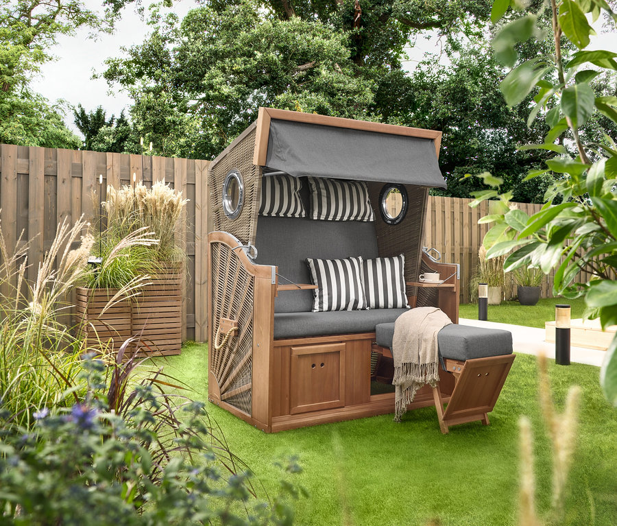 Ein Premium-Strandkorb XL mit 2 Ausklapptischen steht auf einer Wiese, daneben 2 Pflanzsäulen »Tinus«. Im Hintergrund sind 5 LED-Solar-Spieße zu sehen.