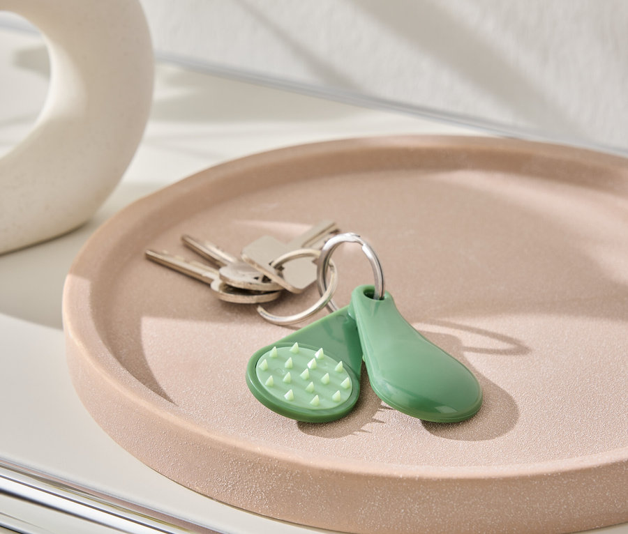 Schlüssel und grüner Schlüsselanhänger liegen auf einem rosafarbenen Teller.